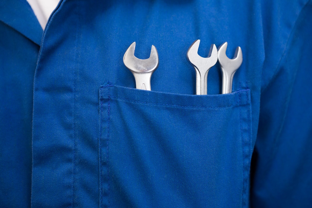 Support et assistance : la blouse d'un technicien comprenant 3 clefs plates de plombier.